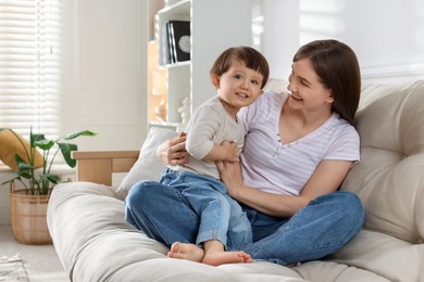 Photo of Happy mother with her cute little son on sofa at home