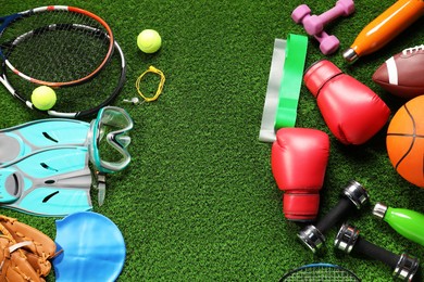 Different sports equipment on artificial grass, flat lay. Space for text