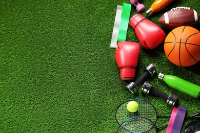 Photo of Different sports equipment on artificial grass, flat lay. Space for text