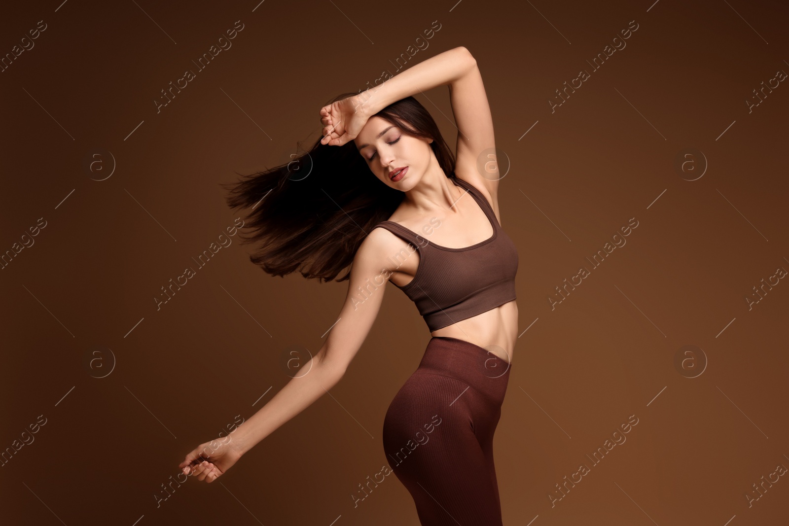 Photo of Beautiful woman in stylish sportswear on brown background