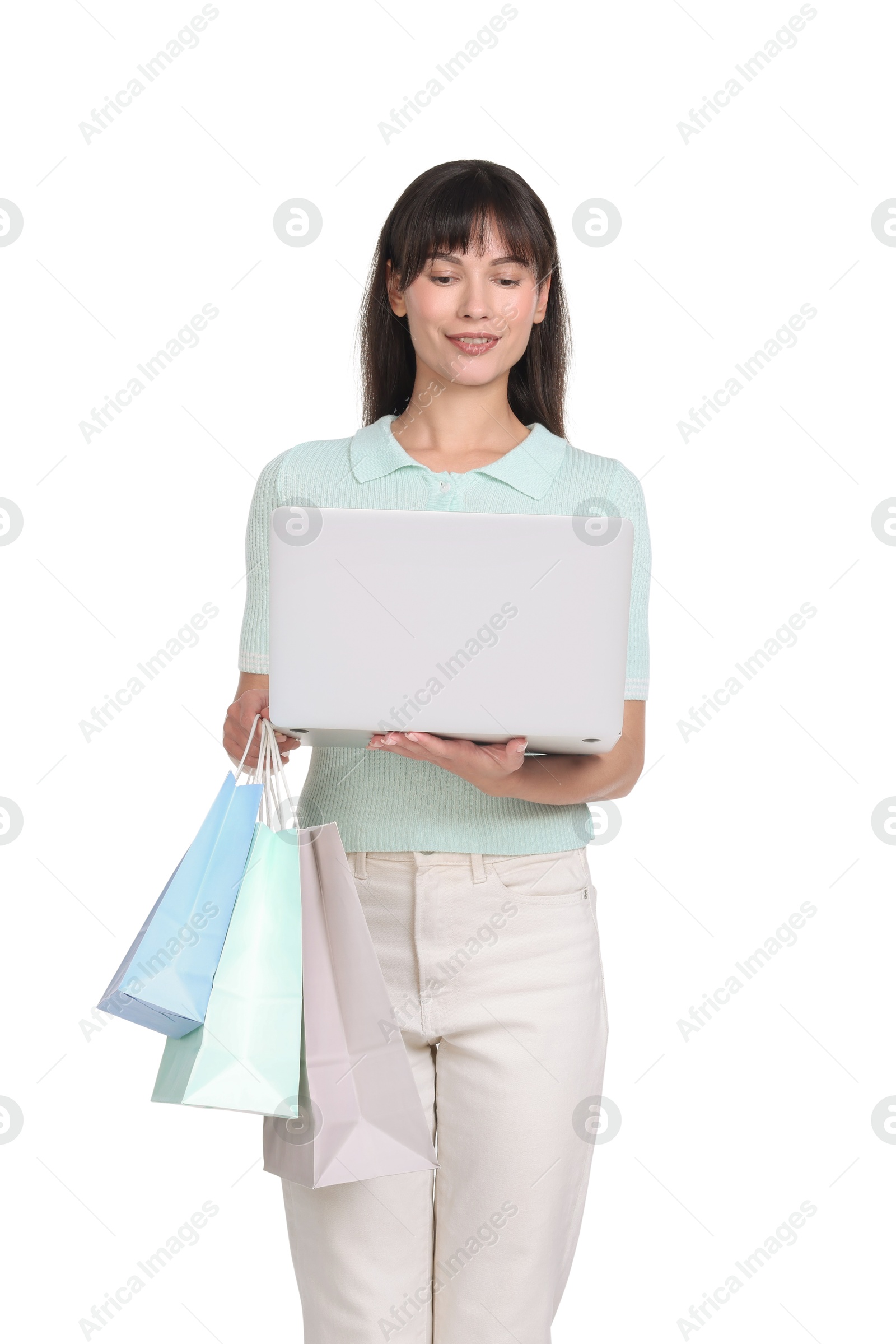 Photo of Internet shopping. Happy woman with laptop and colorful bags on white background