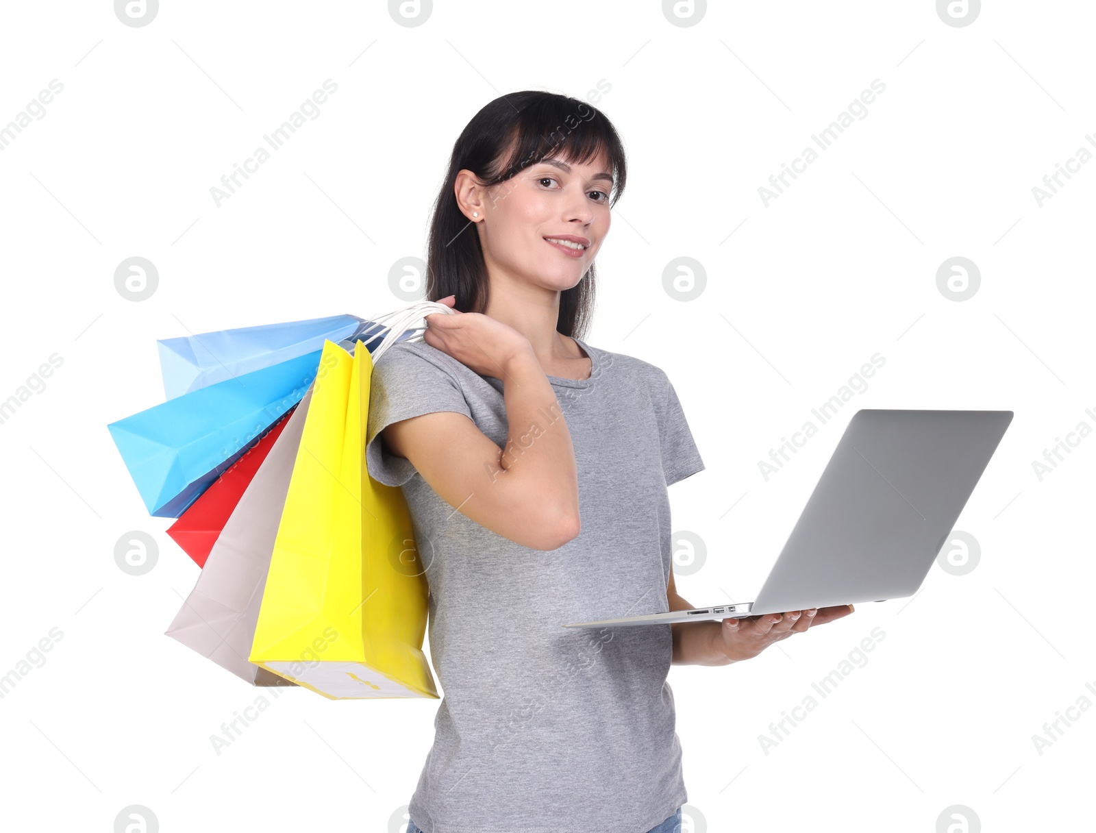 Photo of Internet shopping. Smiling woman with laptop and colorful bags on white background