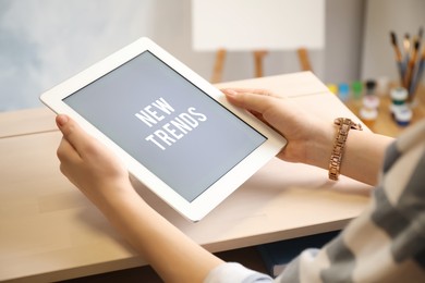 Image of New trends. Woman using modern tablet at table indoors, closeup