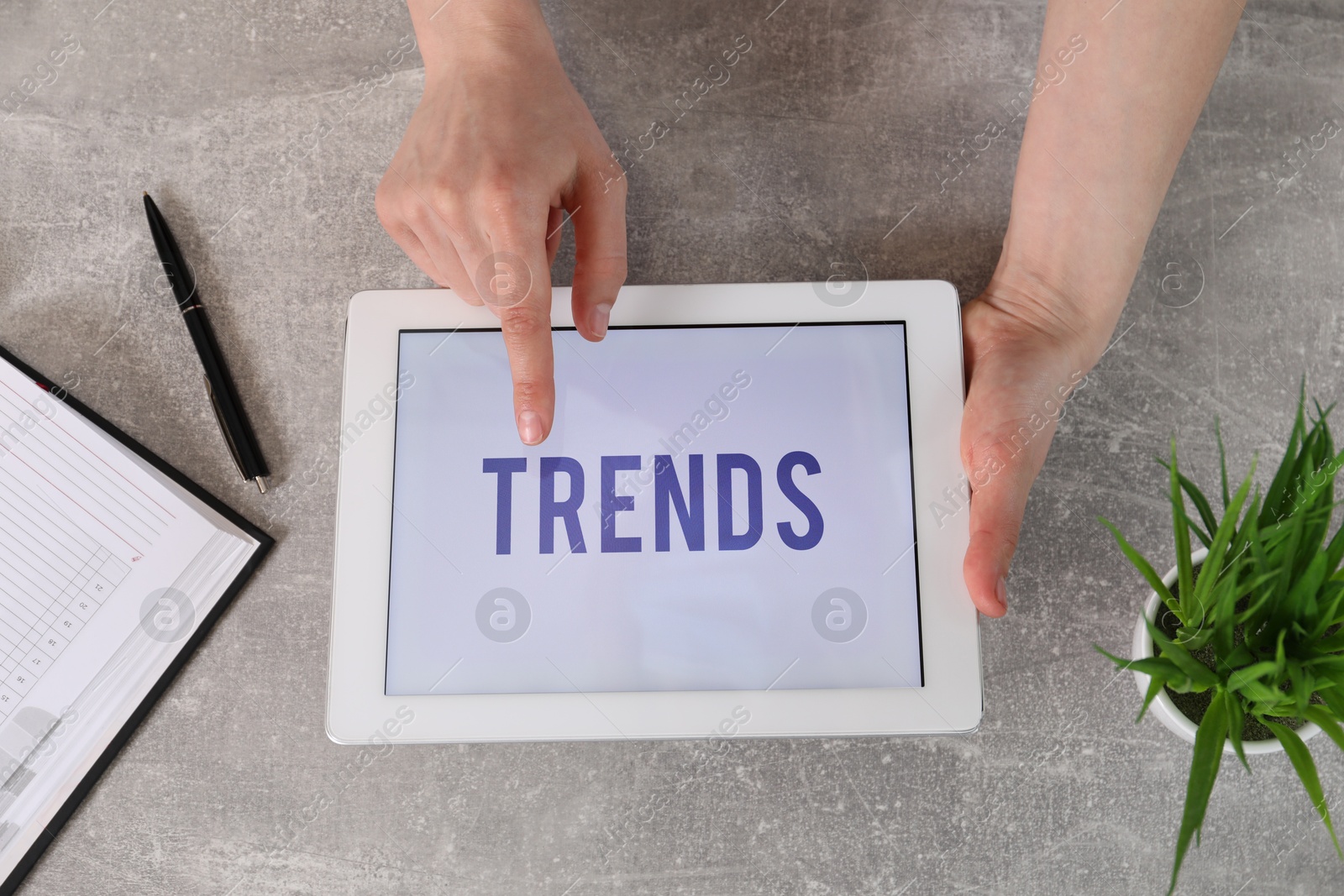 Image of New trends. Woman using tablet at grey table, top view