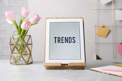 Image of New trends. Modern tablet, stationery and flowers on grey table