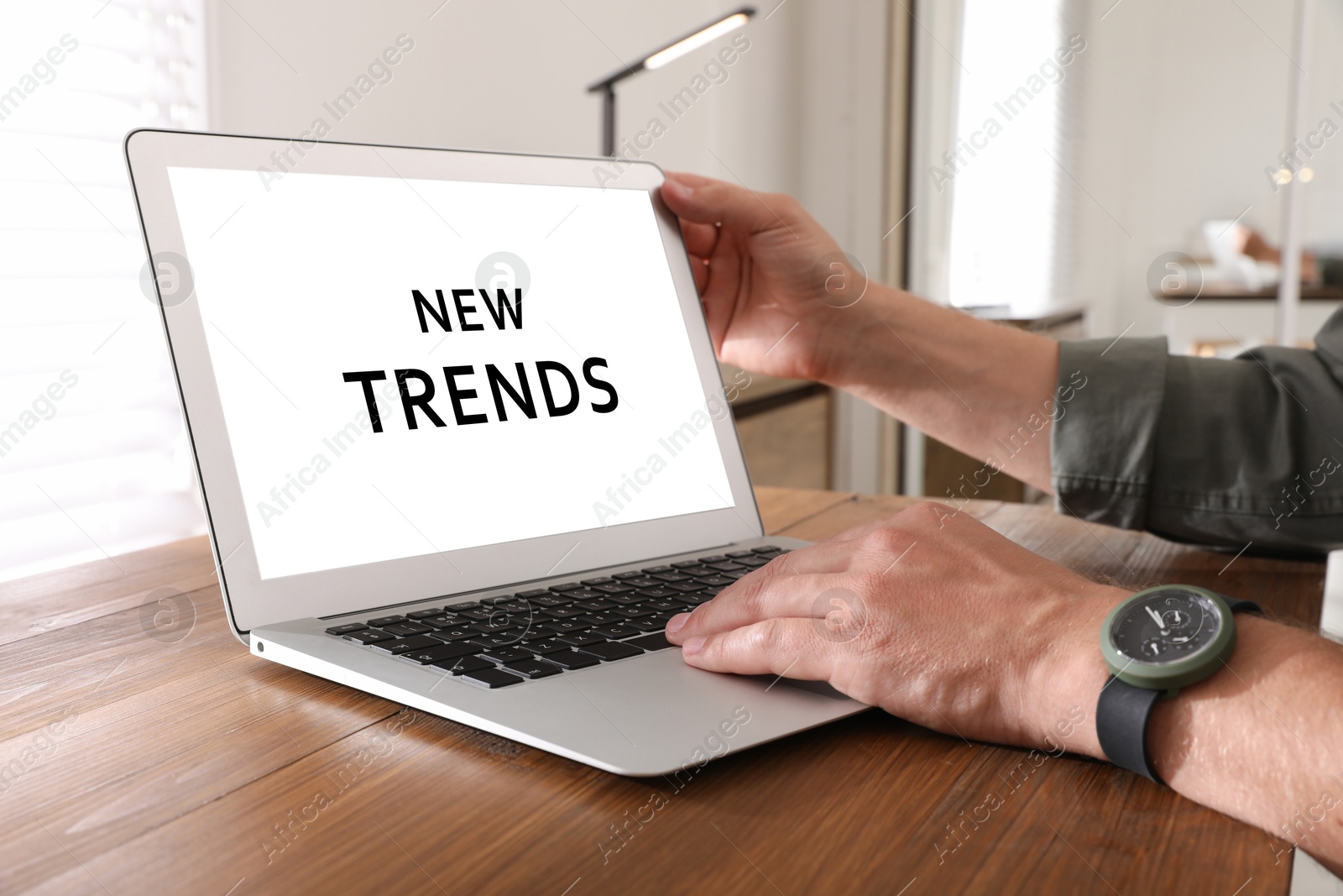 Image of New trends. Man using modern laptop at wooden table indoors, closeup