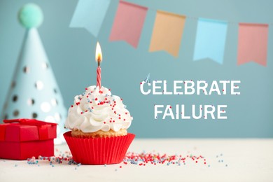 Image of Celebrate failure. Cupcake with burning candle, gift and party cone on white table