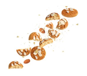 Yummy nut cookies with almond petals in air on white background