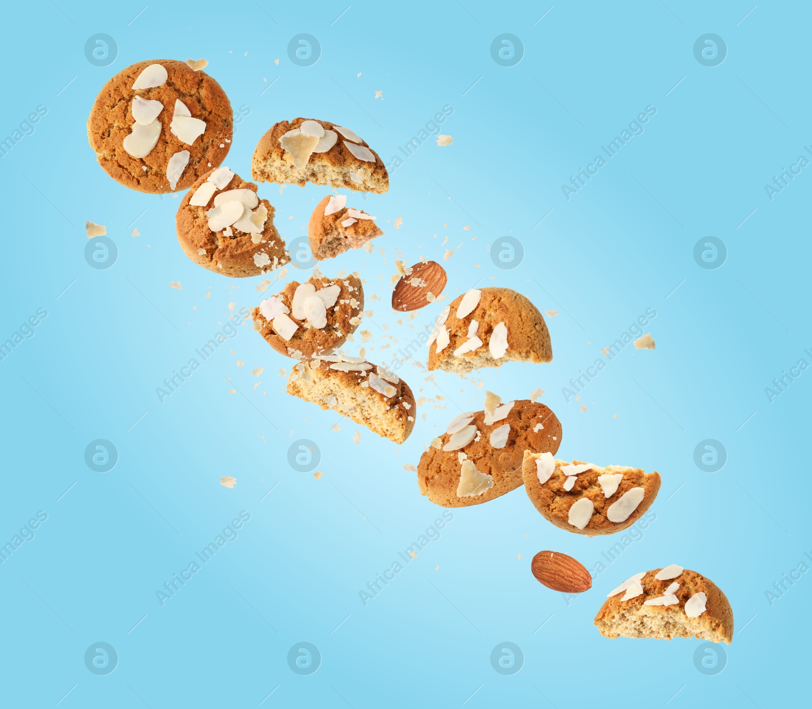 Image of Yummy nut cookies with almond petals in air on blue background