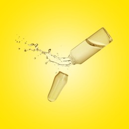 Image of Open ampoule with splashing liquid in air on yellow background