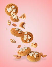 Image of Yummy nut cookies with almond petals in air on coral background