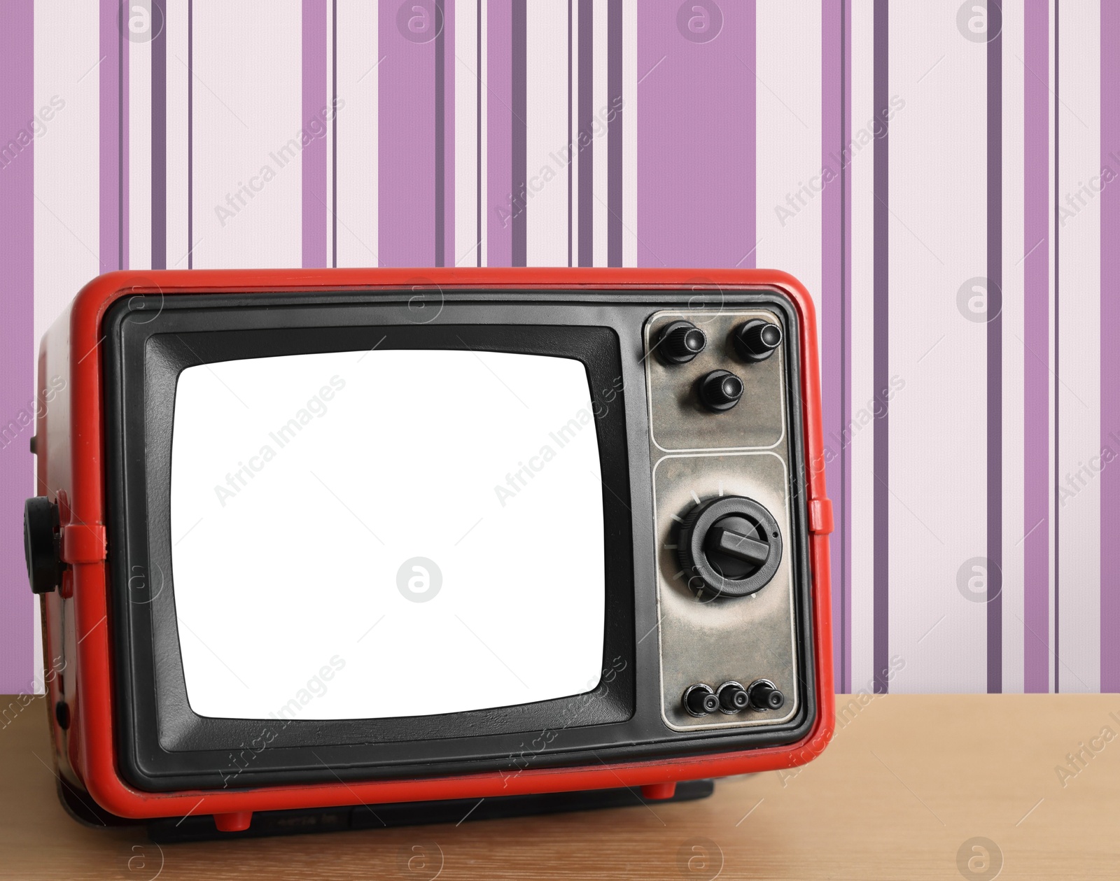 Image of Retro TV on wooden table near wall with vintage style wallpaper. Space for text