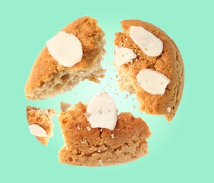 Yummy nut cookie with almond petals in air on aquamarine color background