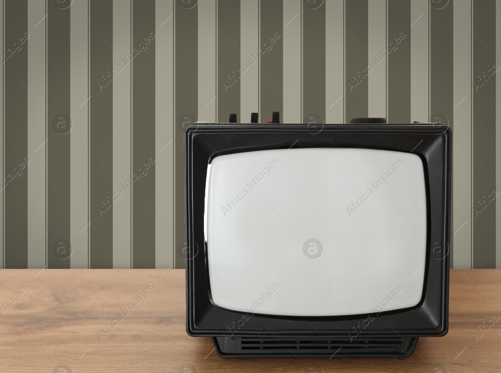 Image of Retro TV on wooden table near wall with vintage style wallpaper. Space for text