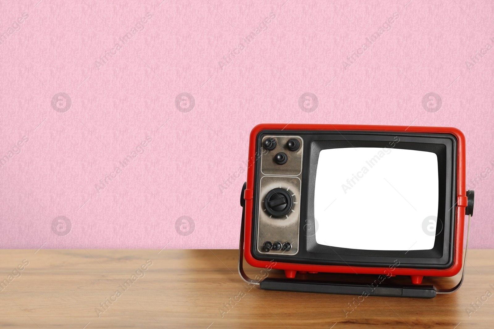 Image of Retro TV on wooden table near wall with vintage style wallpaper. Space for text