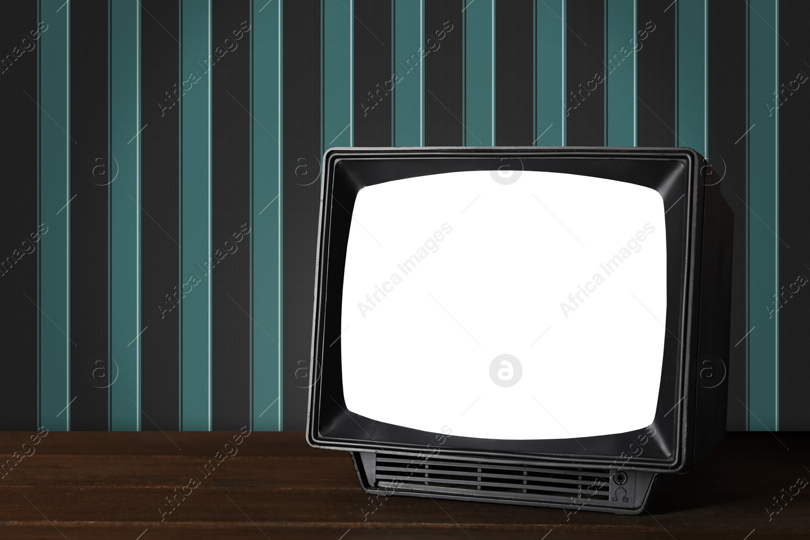 Image of Retro TV on wooden table near wall with vintage style wallpaper. Space for text