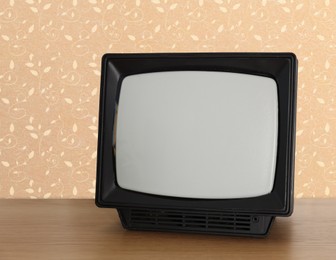 Image of Retro TV on wooden table near wall with vintage style wallpaper