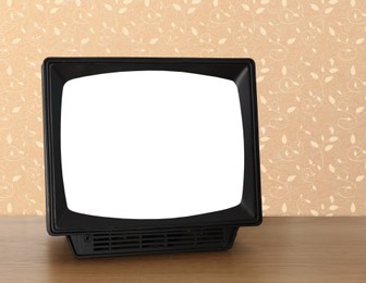 Image of Retro TV on wooden table near wall with vintage style wallpaper