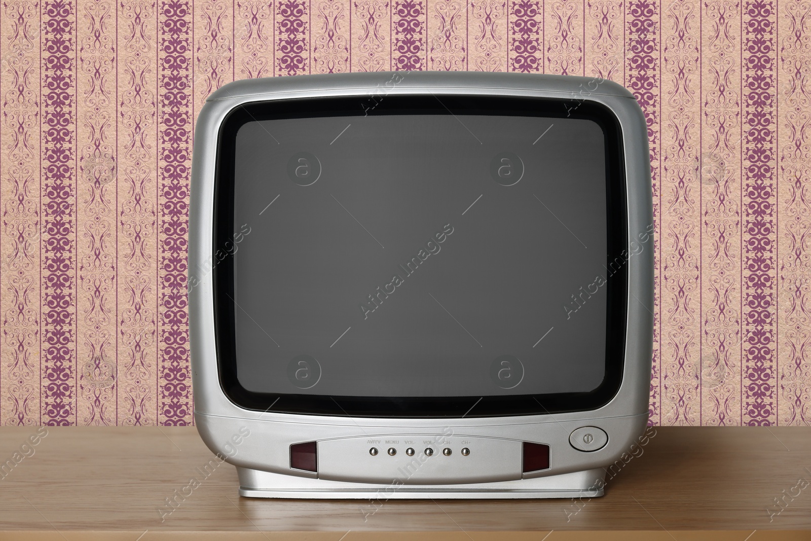 Image of Retro TV on wooden table near wall with vintage style wallpaper