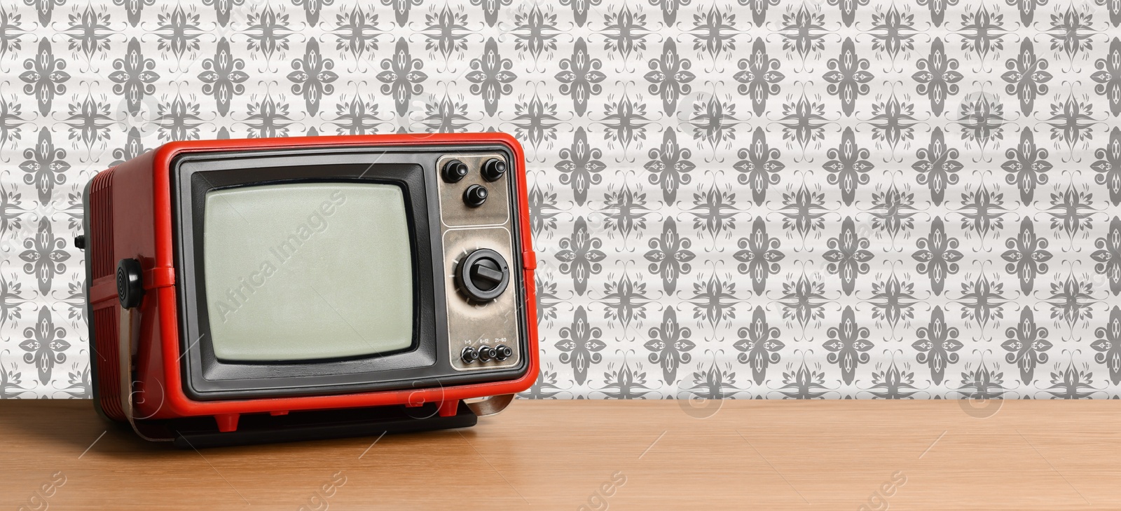 Image of Retro TV on wooden table near wall with vintage style wallpaper. Banner design with space for text