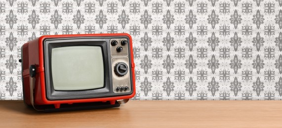 Image of Retro TV on wooden table near wall with vintage style wallpaper. Banner design with space for text