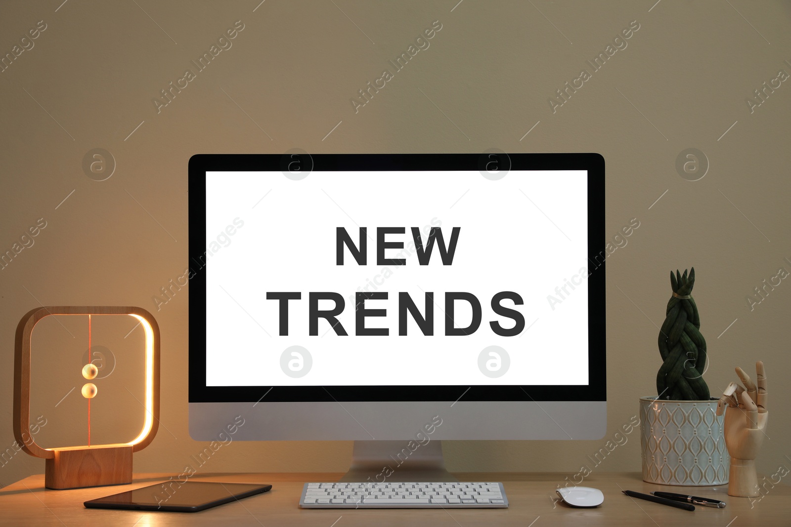 Image of New trends. Comfortable workplace with computer on desk and plant near beige wall