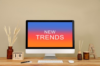 Image of New trends. Modern computer and decor on wooden table near beige wall