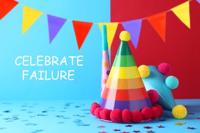 Image of Celebrate failure. Party hats and blower on light blue background