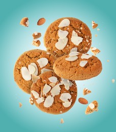 Yummy nut cookies with almond petals in air on turquoise background