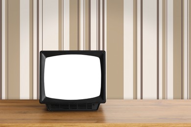 Image of Retro TV on wooden table near wall with vintage style wallpaper. Space for text