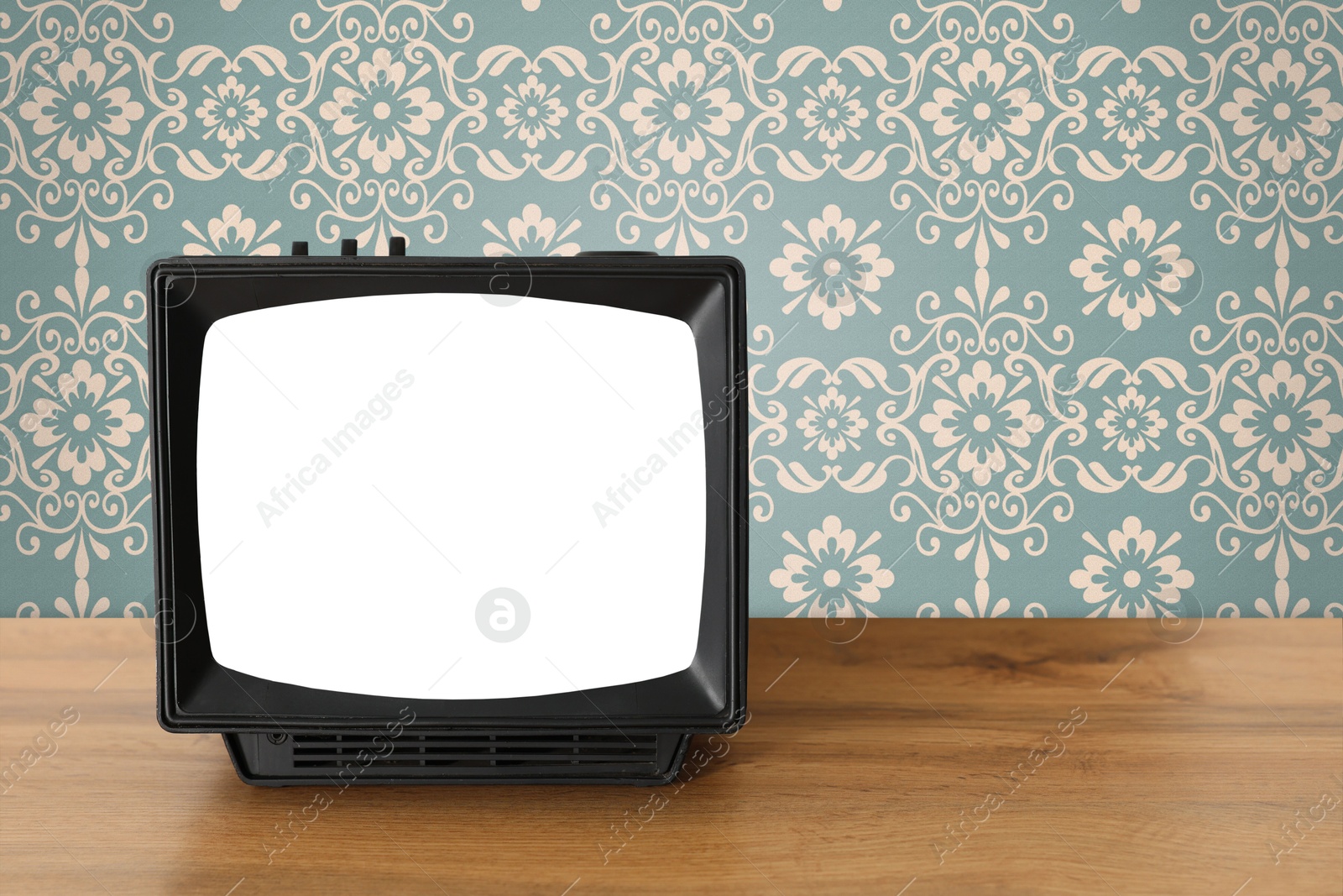 Image of Retro TV on wooden table near wall with vintage style wallpaper. Space for text