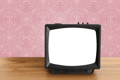 Image of Retro TV on wooden table near wall with vintage style wallpaper. Space for text