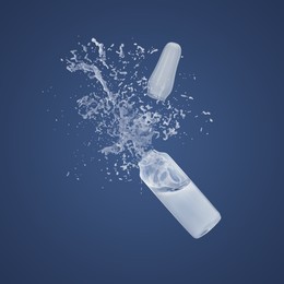 Image of Open ampoule with splashing liquid in air on dark blue background