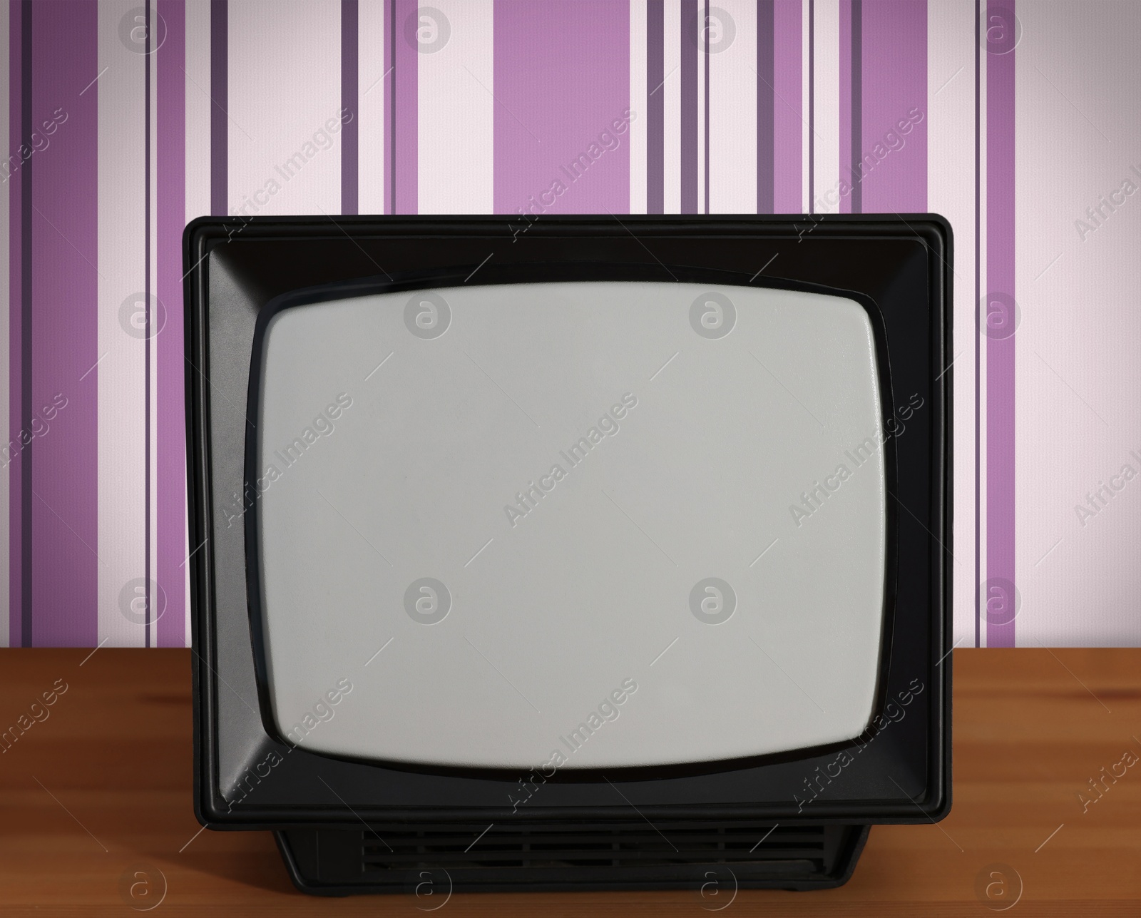 Image of Retro TV on wooden table near wall with vintage style wallpaper