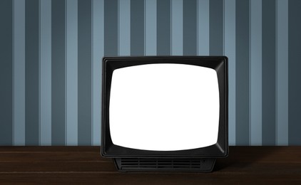 Image of Retro TV on wooden table near wall with vintage style wallpaper