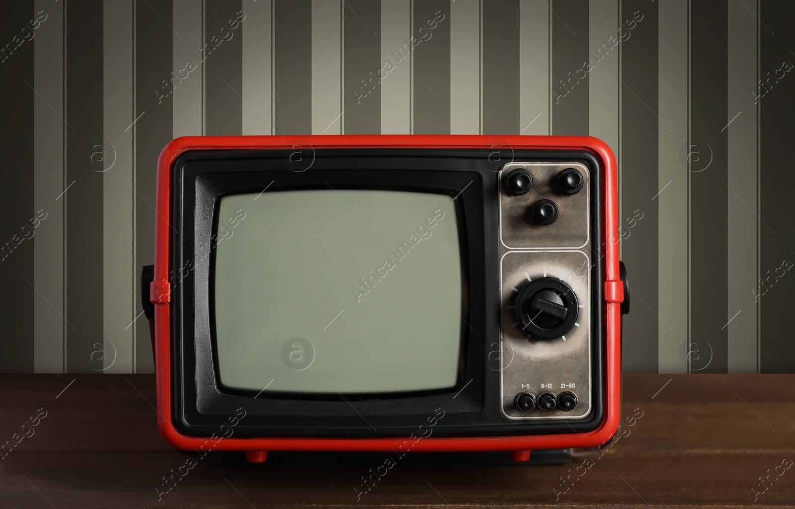 Image of Retro TV on wooden table near wall with vintage style wallpaper