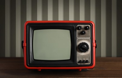 Image of Retro TV on wooden table near wall with vintage style wallpaper