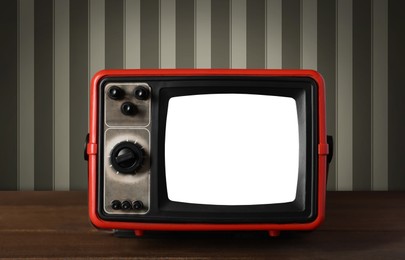 Image of Retro TV on wooden table near wall with vintage style wallpaper