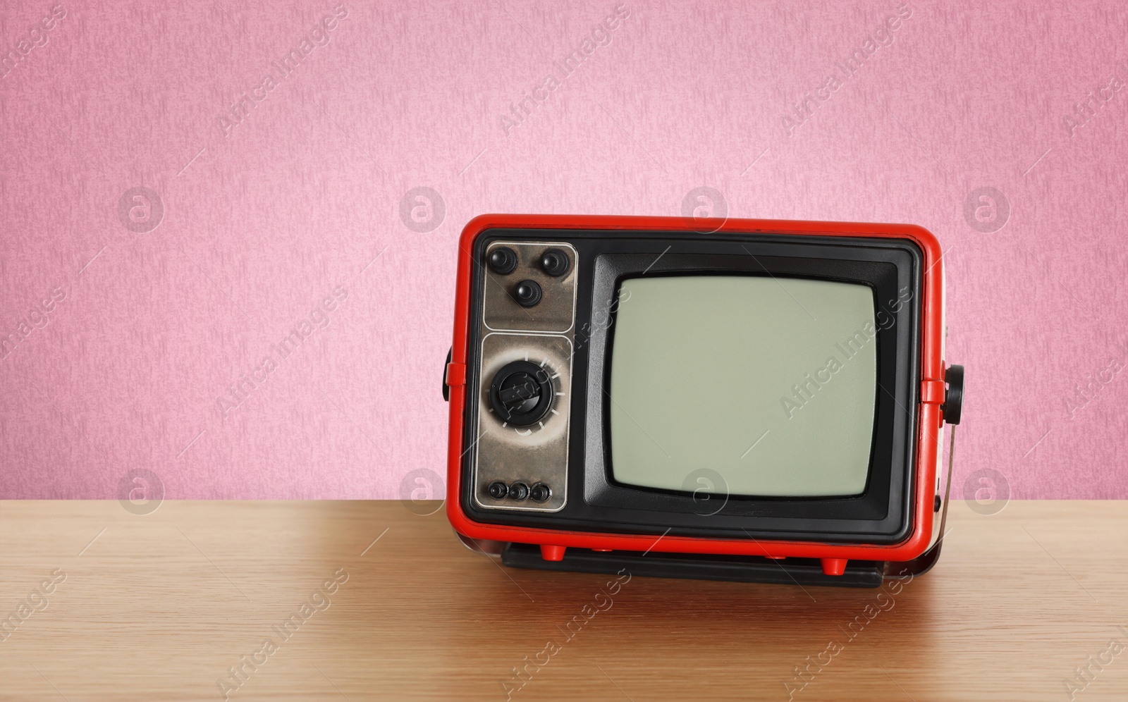 Image of Retro TV on wooden table near wall with vintage style wallpaper. Space for text