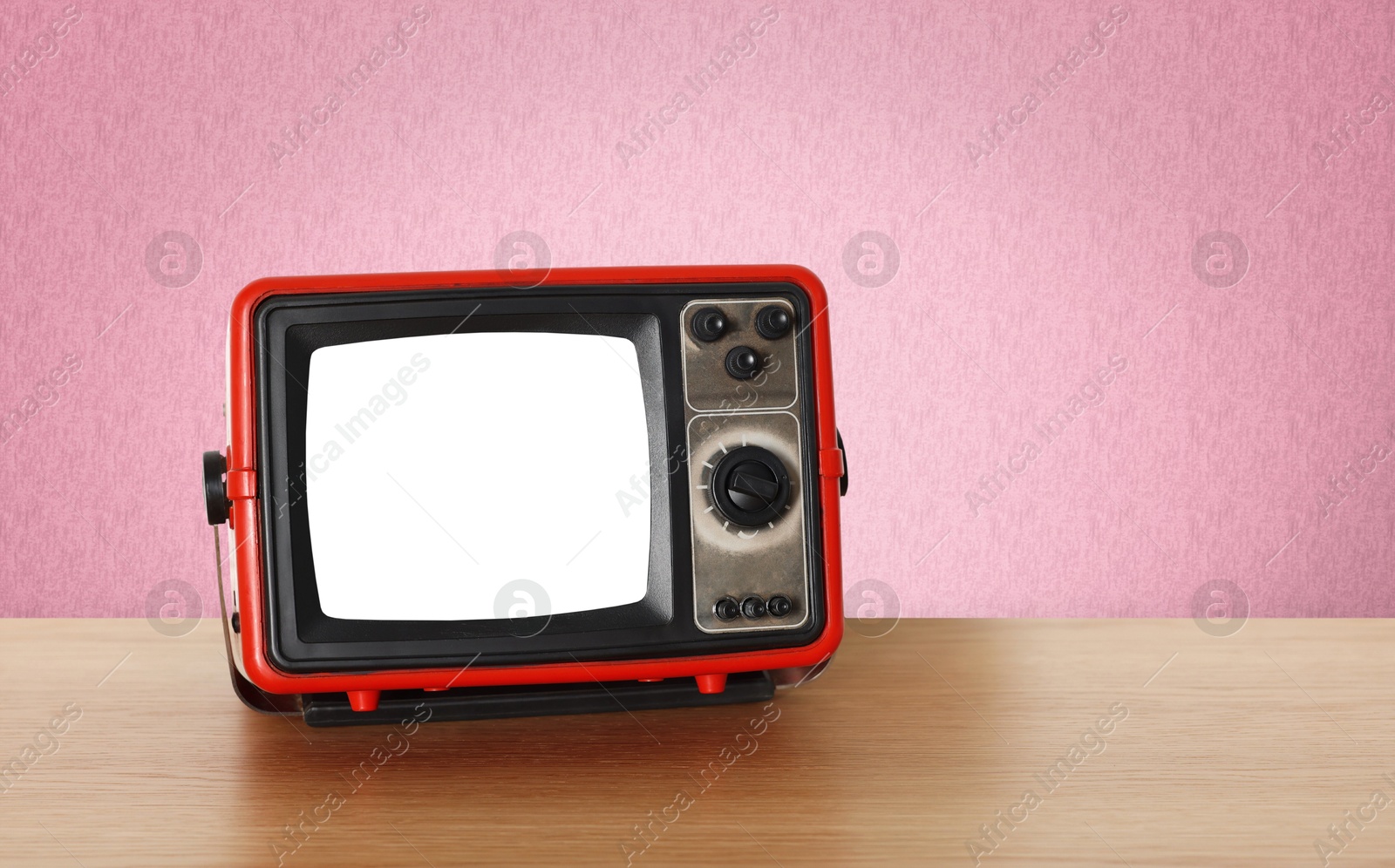 Image of Retro TV on wooden table near wall with vintage style wallpaper. Space for text