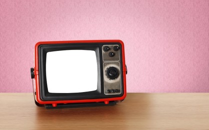 Image of Retro TV on wooden table near wall with vintage style wallpaper. Space for text