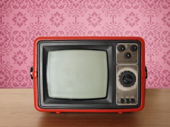 Image of Retro TV on wooden table near wall with vintage style wallpaper