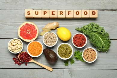 Image of Superfood. Different healthy food products and cubes on grey wooden table, flat lay