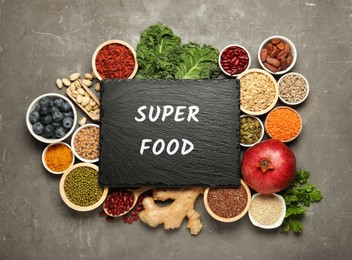 Image of Superfood. Different healthy food products and board on grey table, flat lay