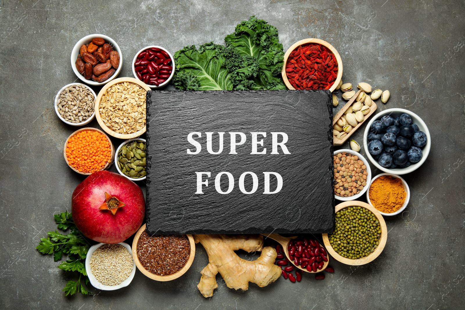 Image of Superfood. Different healthy food products and blank board on grey table, flat lay