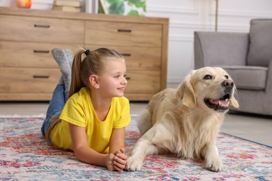 Photo of Girl with cute Golden Retriever dog lying on rug at home