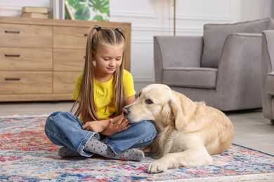 Photo of Girl with her cute Golden Retriever dog on rug at home