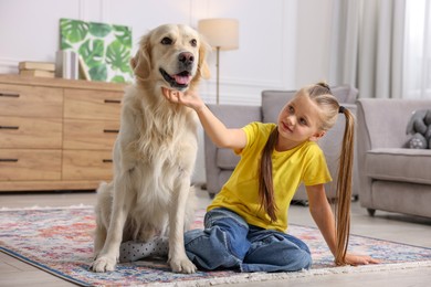 Photo of Girl with her cute Golden Retriever dog on rug at home