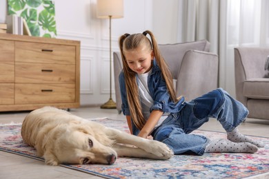 Photo of Girl with her cute Golden Retriever dog on rug at home