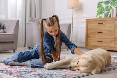 Photo of Girl with her cute Golden Retriever dog on rug at home